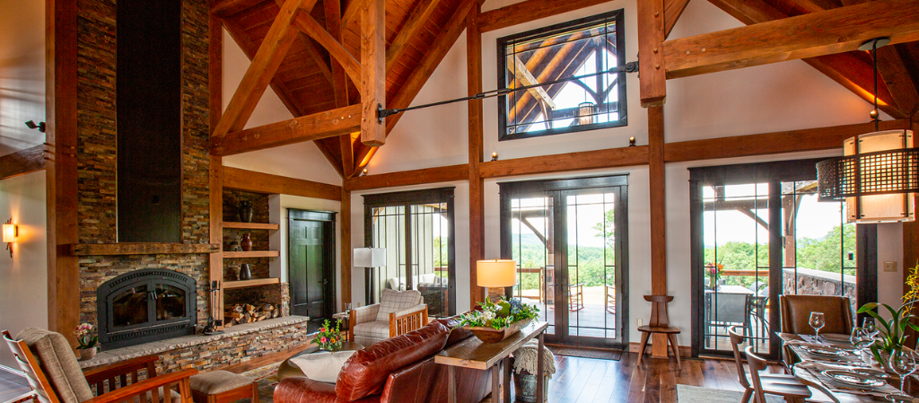 living room with large stone fireplace and leather furniture sitting beneath timber beams