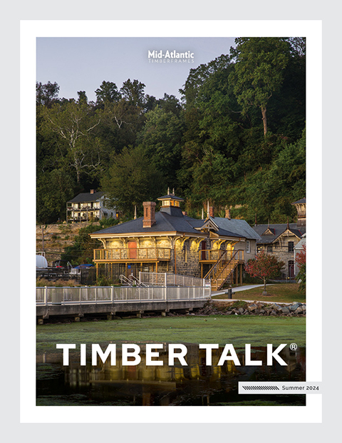Cover of Timber Talk magazine, Summer 2024, showing a scenic lakeside building surrounded by trees and greenery with homes on a hillside in the background during early evening.