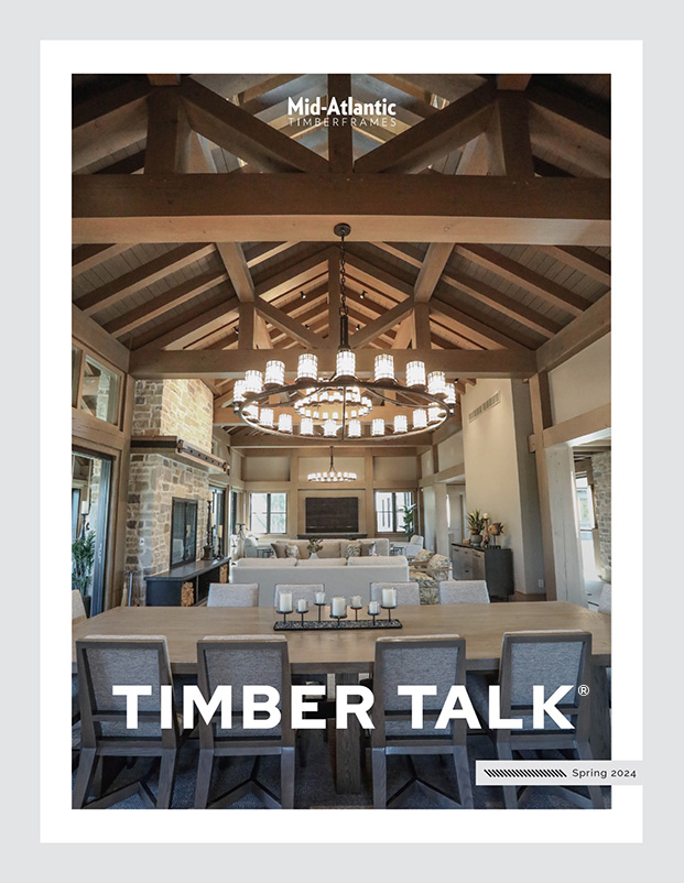 A magazine cover titled TIMBER TALK shows a spacious dining room with exposed wooden beams, a large wooden table, modern chairs, chandeliers, and stone accents. The issue is Spring 2024 from Mid-Atlantic Timber Frames.